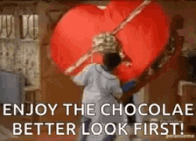 a man is carrying a large red heart on his back .
