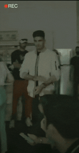 a man in a white jacket is standing in front of a group of people and the word rec is on the bottom