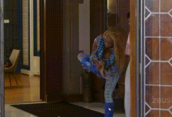 a woman in blue boots is standing in a doorway with her legs crossed .