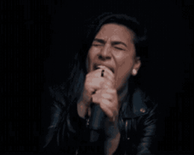 a woman singing into a microphone in a dark room
