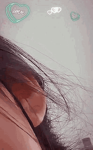 a close up of a woman 's ear with a neon heart that says love on it