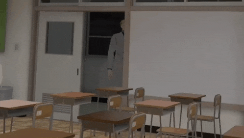 a man in a suit stands in a classroom with empty desks
