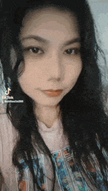 a close up of a woman 's face with long black hair and a t-shirt on .