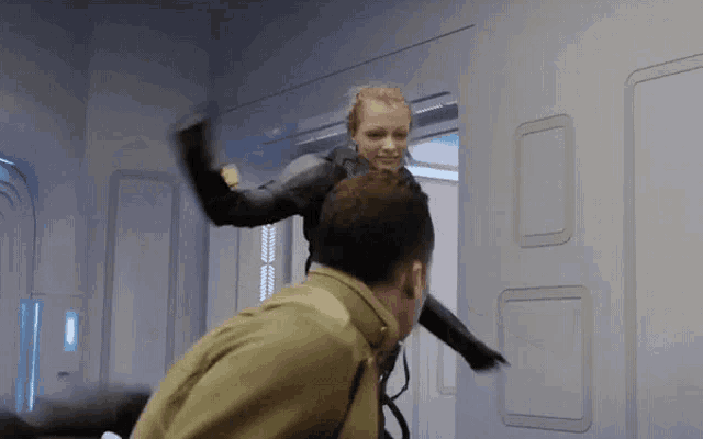 a woman in a black suit is kicking a man