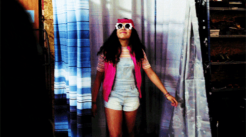 a woman wearing sunglasses and a pink hat is standing in front of a shower curtain