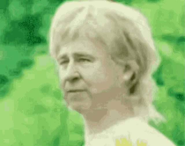 a man with a mullet is standing in front of a green background and looking at the camera .