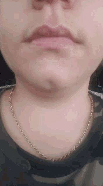 a close up of a woman 's face with a gold chain around her neck