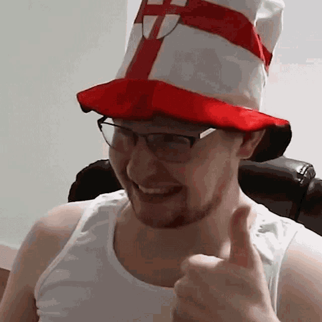 a man wearing a red and white hat with a cross on it gives a thumbs up
