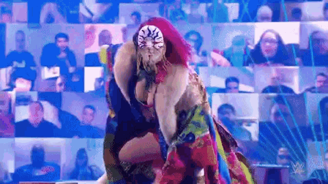 a female wrestler is standing in front of a crowd of people .
