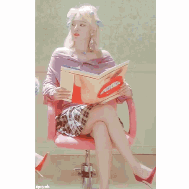 a woman is sitting in a pink chair reading a magazine