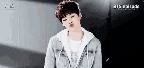 a young boy wearing a denim jacket and a white shirt is making a funny face .