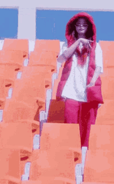 a woman wearing a red vest and pink pants is standing in a stadium .