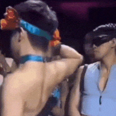 a man wearing sunglasses and a bandana is standing next to a woman wearing a blue shirt .