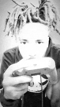 a young man with dreadlocks is holding a video game controller in his hand .