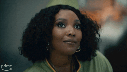 a woman with curly hair is wearing a green jacket and a green hat with the word prime on it