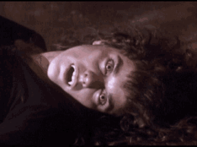a woman is laying on her back with her mouth open and her teeth visible