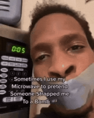 a man with duct tape around his mouth is standing in front of a microwave with the time of 0:05
