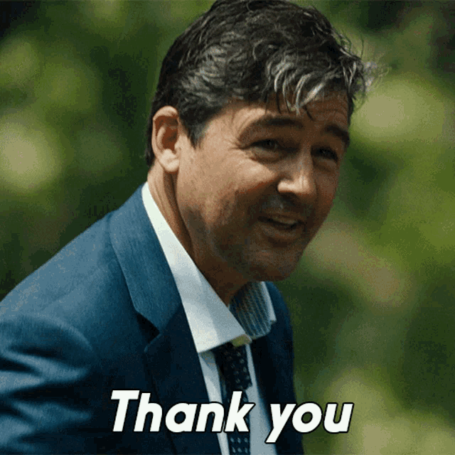 a man in a suit and tie is smiling and says thank you