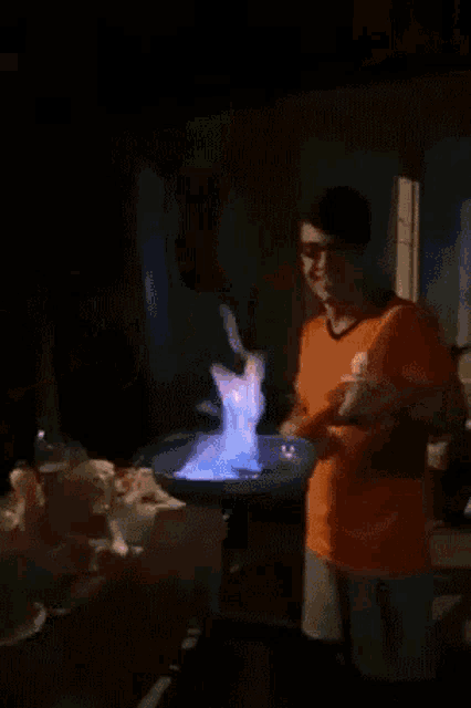 a man in an orange shirt is standing in front of a plate of food that is on fire