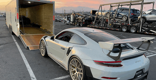 a white porsche is parked in front of a trailer