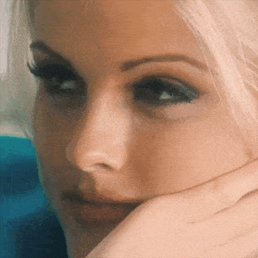 a closeup of a woman 's face with her hand on her chin
