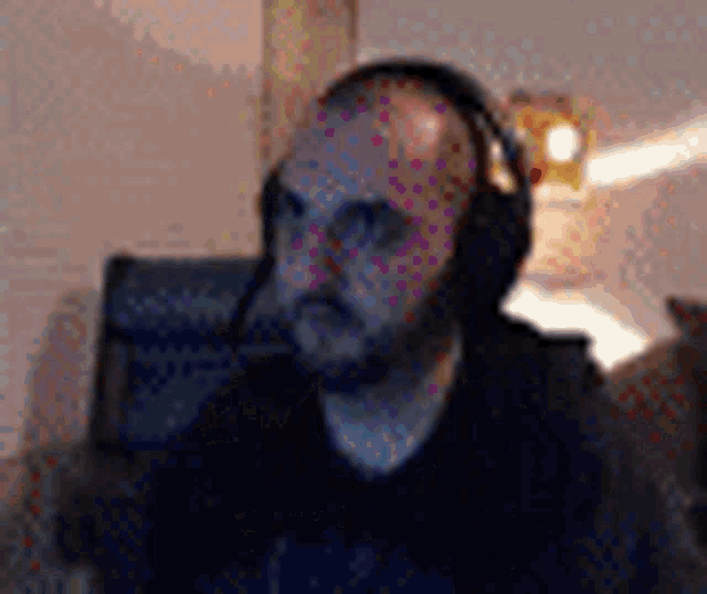 a man with a beard is wearing headphones while sitting on a couch .