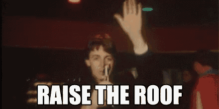 a man is singing into a microphone with the words raise the roof written below him .