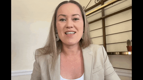 a woman in a tan suit is smiling and looking at the camera