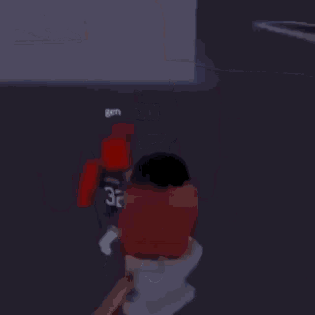a person in a blue shirt with the number 32 on it is standing next to a red roblox character .