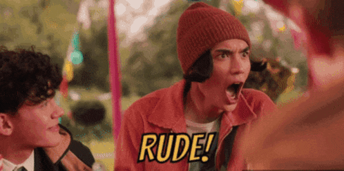 a man wearing a beanie and a red jacket is screaming and saying rude .