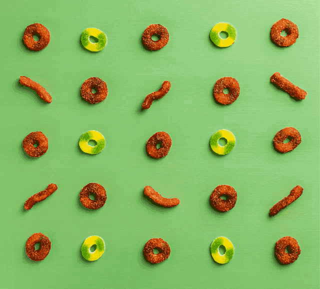 a hand is reaching for a gummy ring on a green background