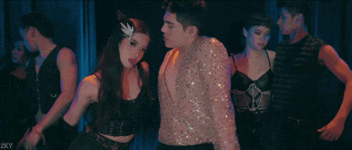 a man in a sequined shirt is dancing with a woman in a black dress