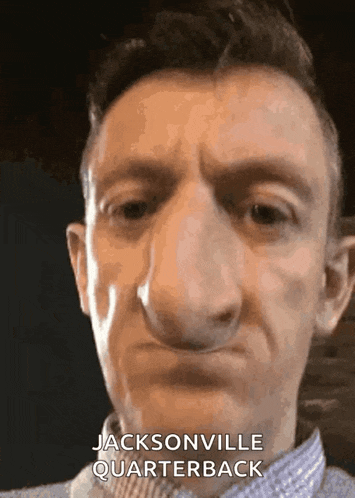 a man with a big nose is wearing a jacksonville quarterback shirt .