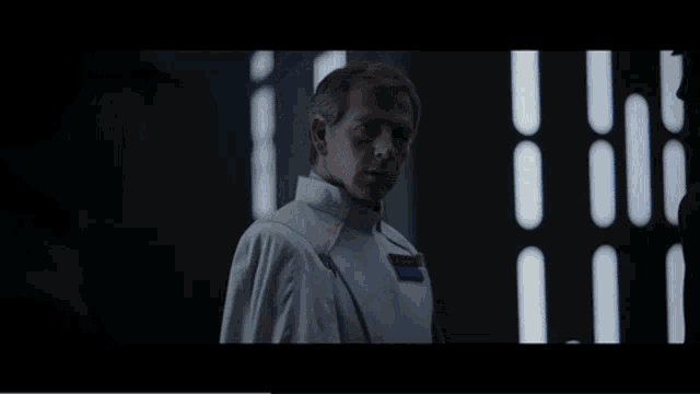 a man in a white uniform says " my achievement " in a dark room