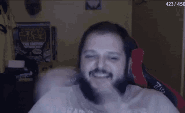a man with a beard is sitting in a red and black gaming chair