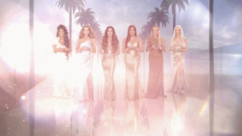 a group of women standing next to each other with palm trees behind them