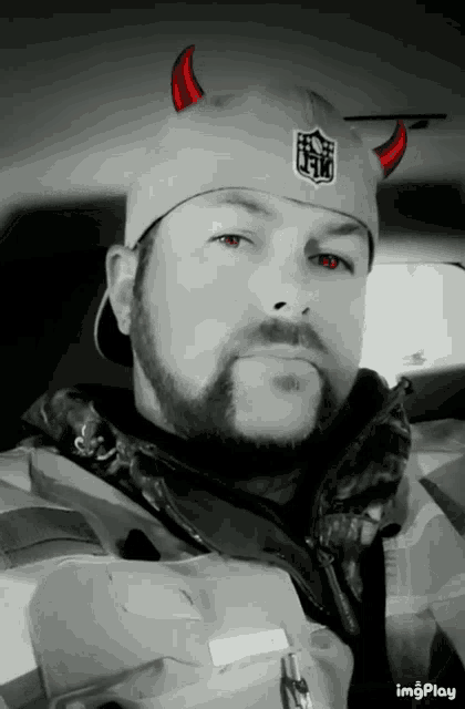 a man wearing a devil horned hat with the nfl logo on it