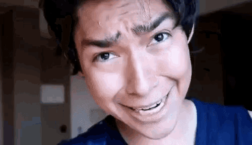a young man is making a funny face with his mouth open and his eyes closed .