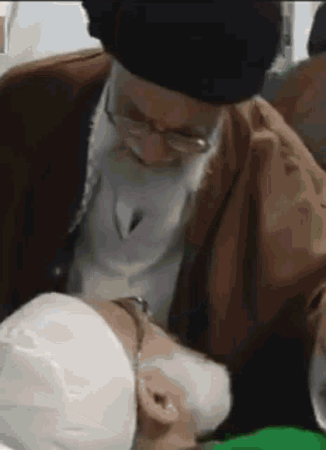 a man with a beard and glasses is kissing a man with a white hat on .