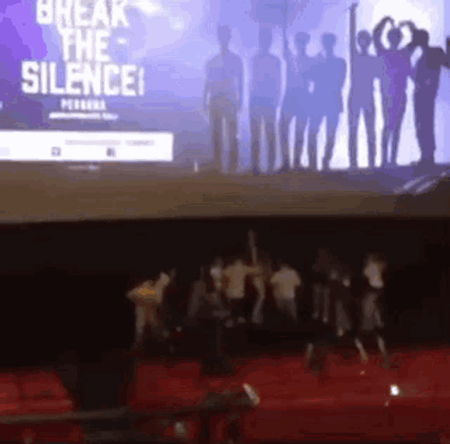 a group of people are dancing in front of a screen that says break the silence