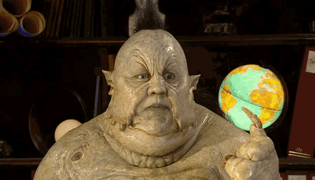 a statue of a man with a mohawk is holding a globe in his hand