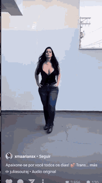 a woman is standing in front of a wall with her hands in her pockets ..