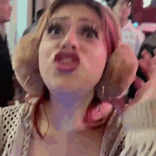 a woman with red hair is making a funny face while standing in front of a crowd .
