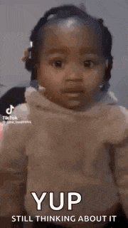 a little girl is smiling and thinking about something while wearing a hoodie .
