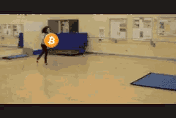 a person is holding a coin with the letter b on it in a gym