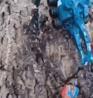 a blue toy robot is sitting on a rock .