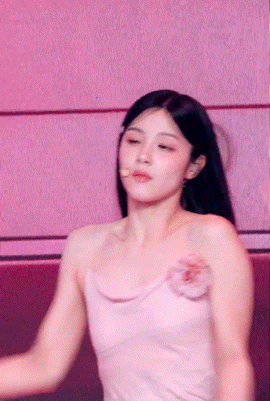 a woman in a pink dress with a flower on her shoulder