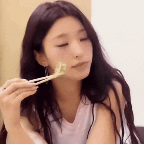 a woman is eating something with chopsticks and looking at the camera