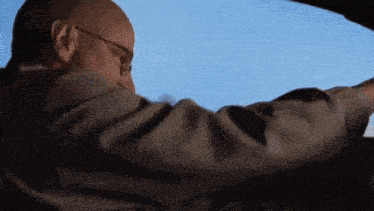 a man wearing glasses looks out the window of a car