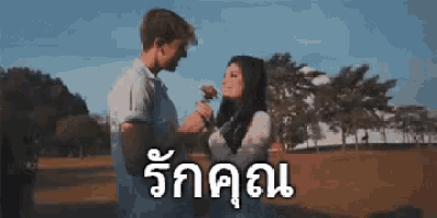 a man is giving a rose to a woman in a park in a blurry photo .